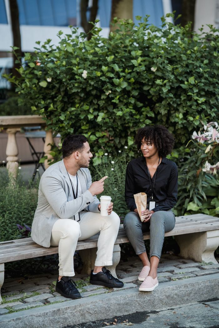 A man and woman enjoy a casual conversation on a park bench, creating a lively urban atmosphere.